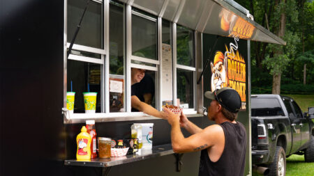 A man receiving a dish of food from Rollin Smoke food truck at Food Truck Festival at Garden Drive-In Theater in Hunlock Creek, PA.
