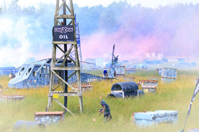 A paintball player walks off the field doused with pink and blue smoke bombs during Skirmish Paintball's scenario game, 