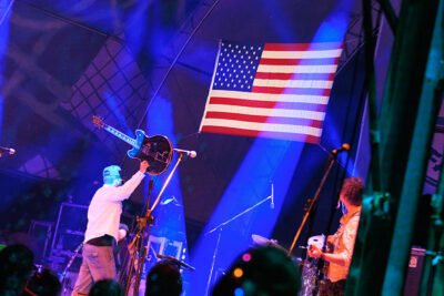 A guitar player raises his guitar on stage in front of an American Flag at the Briggs Farm Blues Festival in Nescopeck, PA.
