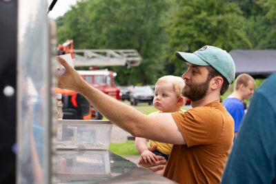 A man holding a baby picking up a basket of food
