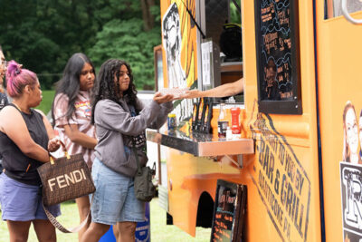 A woman receiving a basket of food from R-Bar & Grill food truck