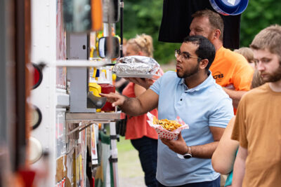A man holds a basket of fries at Maddys Doghouse food truck