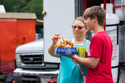 A boy holds a dog dish piled with fries from Maddy's Doghouse