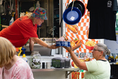 A woman handing over a dog dish of food from Maddy's Doghouse