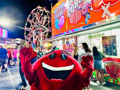 The Tomato Mascot poses along the midway among rides and food stands at the Pittston Tomato Festival in Pittston, PA.