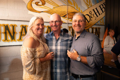 Three people pose for a photo holding glasses of beer
