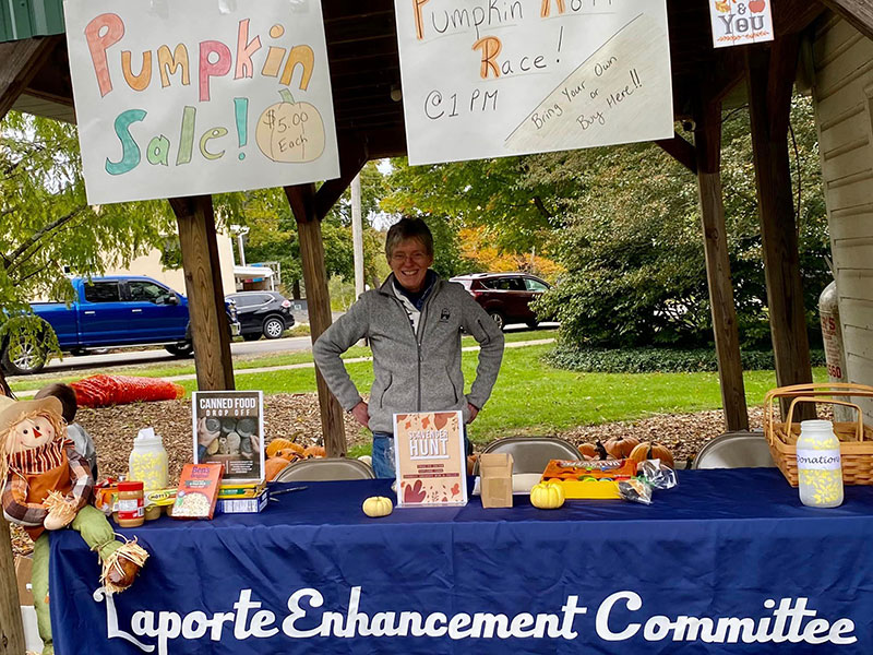 A woman at a tent welcomes visitors to the Laporte Enhancement Committee Pumpkin Festival in Laporte, PA.