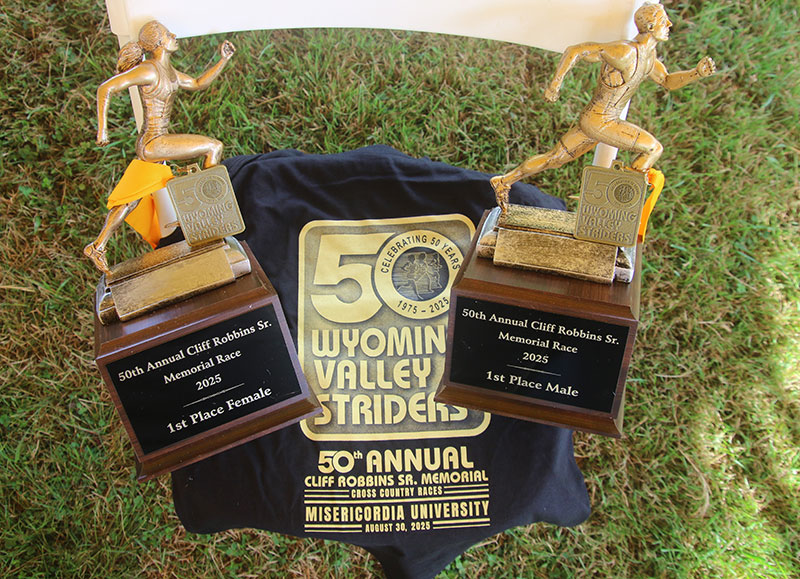 The Cliff Robbins Sr. Memorial first-place trophies, awarded to the top male and female runners, feature a wooden base and gold runners.