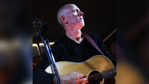 Promotional photo for Charles Havira with Nick Driscoll and Justin Mazer at The Exchange in Bloomsburg, featuring a musician playing acoustic guitar in a softly lit setting.