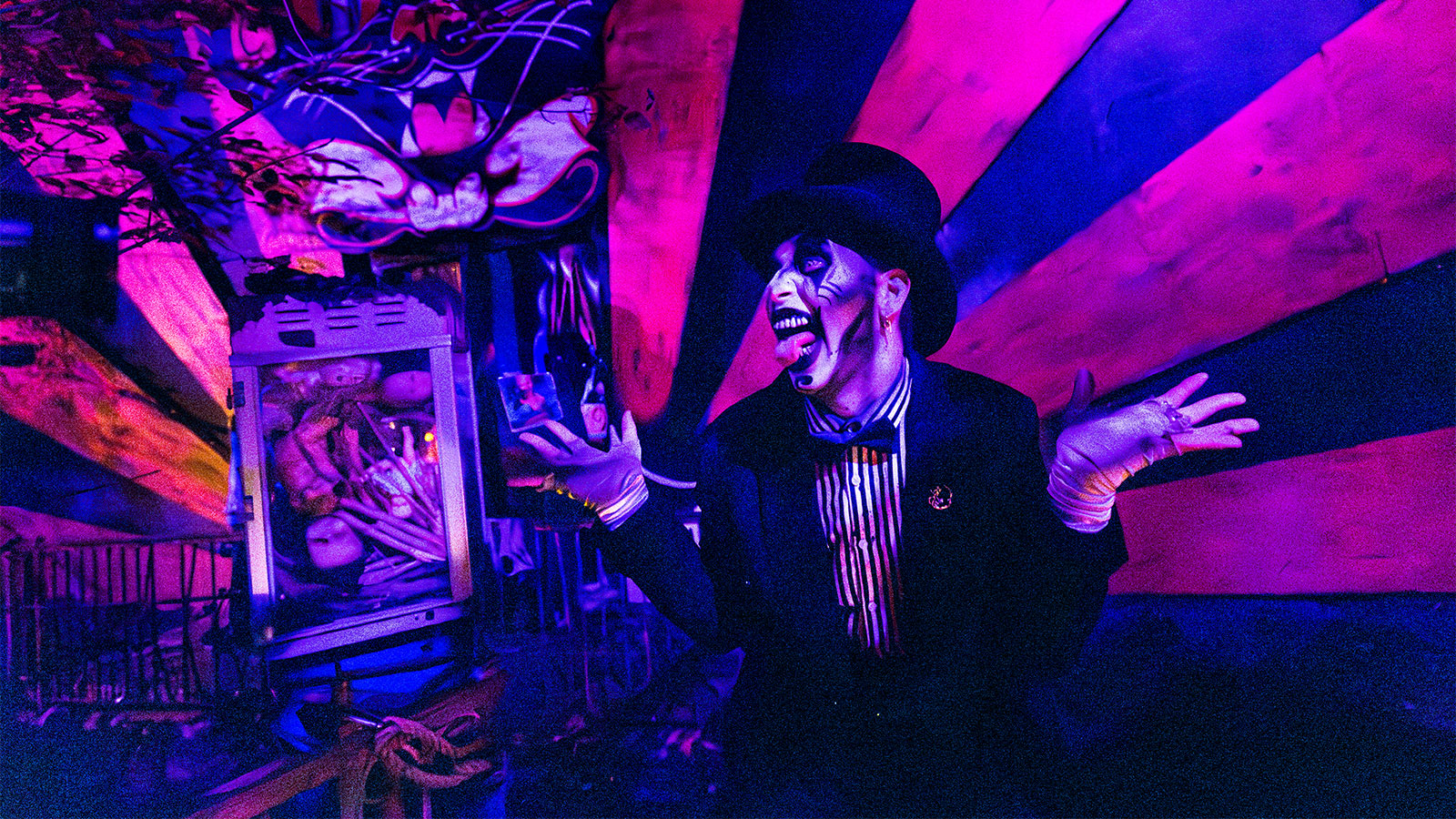 An actor dressed as a creepy clown with a top hat smiles and sticks his tongue out at the crowd at Reaper's Revenge in Scott Twp., PA near Scranton.