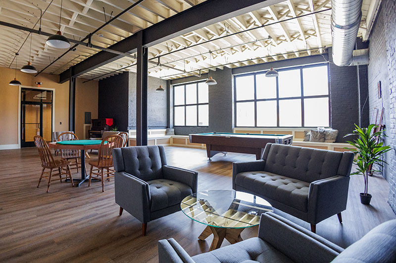A view into the community room with seating areas, a pool table and a poker table at the Waterfront Warehouse in Pittston, PA.