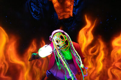 An actor dressed as a clown stands in a room with paintings fire in neon colors on the wall at Reaper's Revenge in Scott Twp., PA near Scranton.