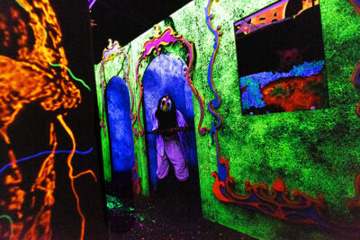 An actor dressed in neon colors under a blacklight stares at the camera at Reaper's Revenge in Scott Twp., PA near Scranton.