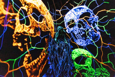 An actor stands in a black room with neon skulls and squiggly lines on the wall at Reaper's Revenge in Scott Twp., PA near Scranton.