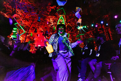 An actress dressed in neon colors under a blacklight smiles creepily at the crowd on a hayride at Reaper's Revenge in Scott Twp., PA near Scranton.