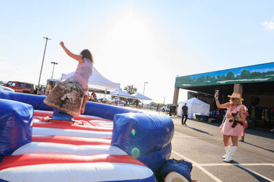 A woman rides a mechanical bull while her friend takes her picture during the Boots & Brews Music Festival at Clubhouse 315 in Wilkes-Barre, PA.