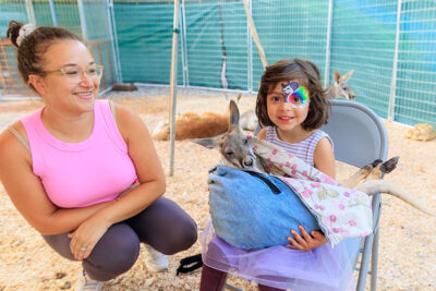 A girl smiles for the camera as she holds a baby kangaroo at the Luzerne County Fair in Dallas, PA.