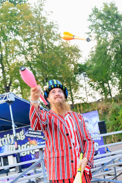 A man in a striped suit and top hat juggles bowling pins at the Luzerne County Fair in Dallas, PA.