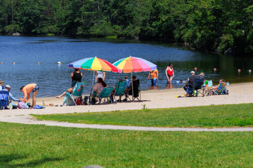 Beach-goers sit under umbrellas at Tobyhanna State Park in Tobyhanna, PA.