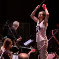 Promotional image for Battle of the Bands presented by the Northeastern Pennsylvania Philharmonic at Mohegan Pennsylvania Casino in Wilkes-Barre, showing a conductor leading musicians during an orchestral performance.