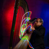 Celtic & Bluegrass Sky at the Kirby Center for Creative Arts in Kingston, PA, takes place on March 12 and is depicted with a musician playing a harp surrounded by colorful light trails against a red and blue backdrop.