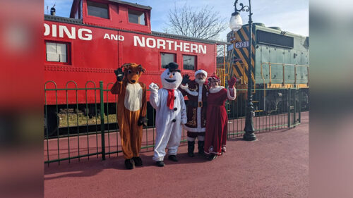 Santa Claus Special on the Reading Blue Mountain & Northern Railroad with Santa, Mrs. Claus, Frosty, and Rudolph waving beside the bright red train.