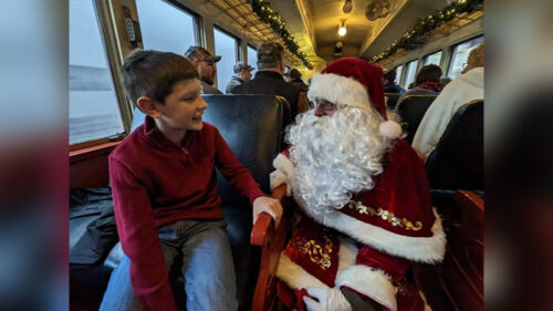 A boy talking with Santa in the train coach seat on the Santa Claus Special train ride in Minersville, PA.