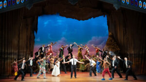 The cast of The Book of Mormon, presented by Broadway Theatre League in Scranton, PA, performs a lively musical number on stage with colorful lighting and energetic choreography.