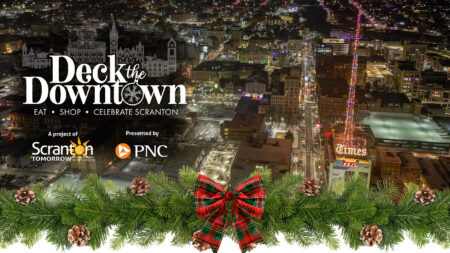 A graphic image featuring an aerial view of Downtown Scranton at night during Christmas with a holiday wreath superimposed to the image and the text: 
