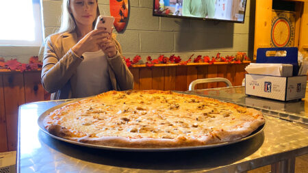 A woman taking a photo of the giant Pig Out pizza from Uncle Bucks BBQ in Plymouth, PA.