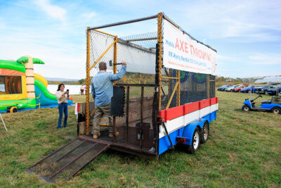 A man throws an axe in the back of a mobile axe throwing trailer while a woman takes his picture at Dymond's Farm and Farm Market in Dallas, PA.
