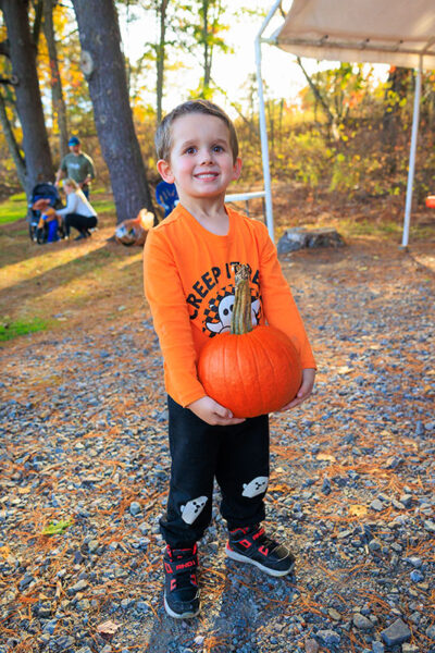 A young boy smiles at the camera while holding a pumpkin at Dymond's Farm and Farm Market in Dallas, PA.