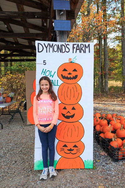 A girl stands in front of a height chart decorated with pumpkins at Dymond's Farm and Farm Market in Dallas, PA.