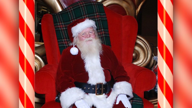 Photo of Santa Claus sitting in a large red chair with a plaid blanket draped over the back during Santa’s Arrival at the Wyoming Valley Mall.