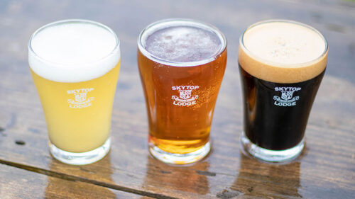 Three glasses of beer on a wooden table during Winter Beer Fest at Skytop Lodge in Skytop, PA, with Skytop Lodge logos visible on the glasses.