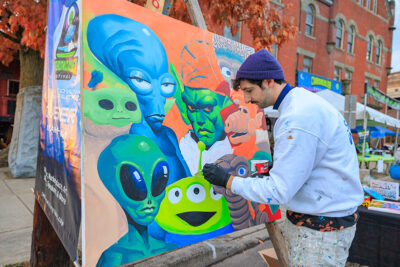 An artist paints famous alien characters on a canvas during the second annual Carbondalien Festival in Carbondale, PA.