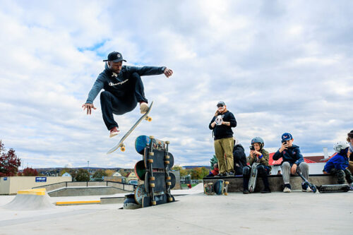 A skateboarder jumps over six skateboards that are stacked on their side at the new Weston Field Skate Park in Scranton, PA.