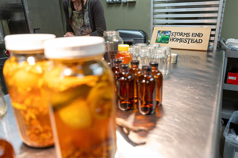 Jars of herbal products from Storms End Homestead displayed on a stainless steel worktable at the Hazleton Kitchen Incubator in Hazleton, PA.