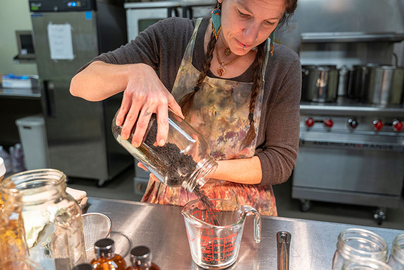 Storms End Homestead founder measuring dried herbs during small-batch production at the Hazleton Kitchen Incubator in Hazleton, PA.