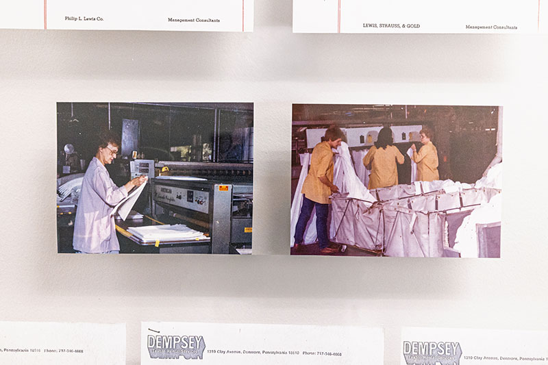 Historic photos displayed inside Dempsey Uniform & Linen Supply’s offices in Jessup, PA, showing early plant operations.