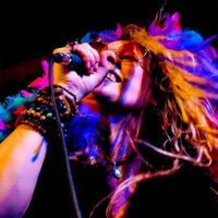 Promotional image for Experience Janis – The Tribute to Janis Joplin at Mauch Chunk Opera House in Jim Thorpe, showing a singer holding a microphone with colorful lighting and expressive movement.