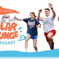 Participants jumping into icy water during the Northeast Polar Plunge at Montage Mountain Resorts in Scranton, PA, with the “Polar Plunge Northeast” Special Olympics logo visible.