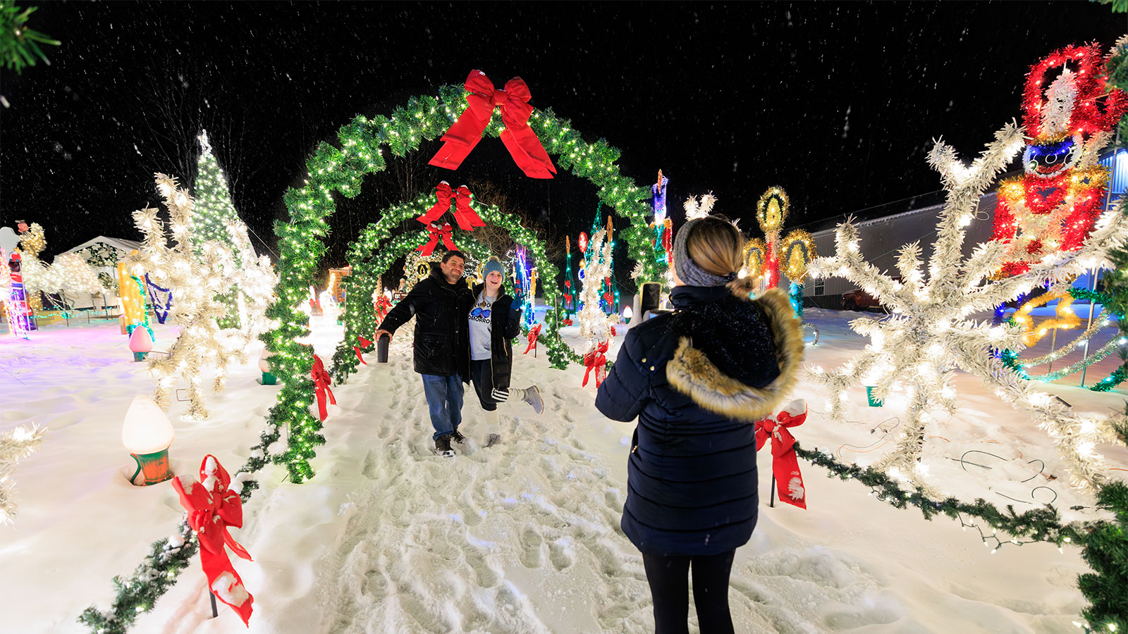 A couple poses for a photo under a tunnel of Christmas wreaths at the Saint Nick's Display in Waymart, PA.