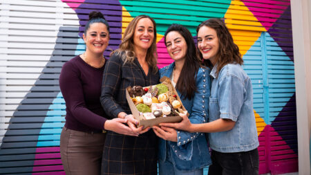 Four woman pose with their cookie box from The Lynn Sisters Holiday Cookie Box.