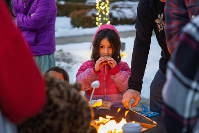 A little girl in a pink coat enjoys her s'more during the Merry and Bright event at Marywood University in Scranton, PA.