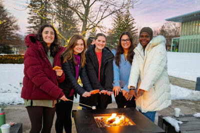 A group of students warm their hands over the fire during the Merry and Bright event at Marywood University in Scranton, PA.