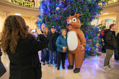 A group of people post with a guy in an inflatable reindeer costume in front of the Christmas Tree during the Merry and Bright event at Marywood University in Scranton, PA.