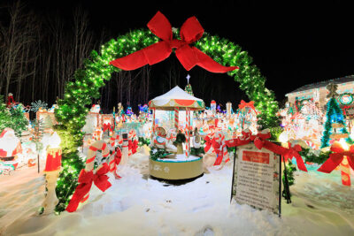A mini merry-go-round lights up under a giant walkthrough Christmas wreath at the Saint Nick's Display in Waymart, PA.