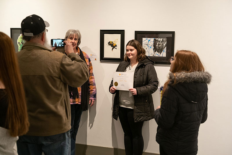 A young artist poses with her award in front of her original artwork at the Everhart Museum in Scranton, PA.
