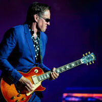 Joe Bonamassa playing an electric guitar onstage under blue and purple lighting, appearing at the F.M. Kirby Center in Wilkes-Barre, PA.